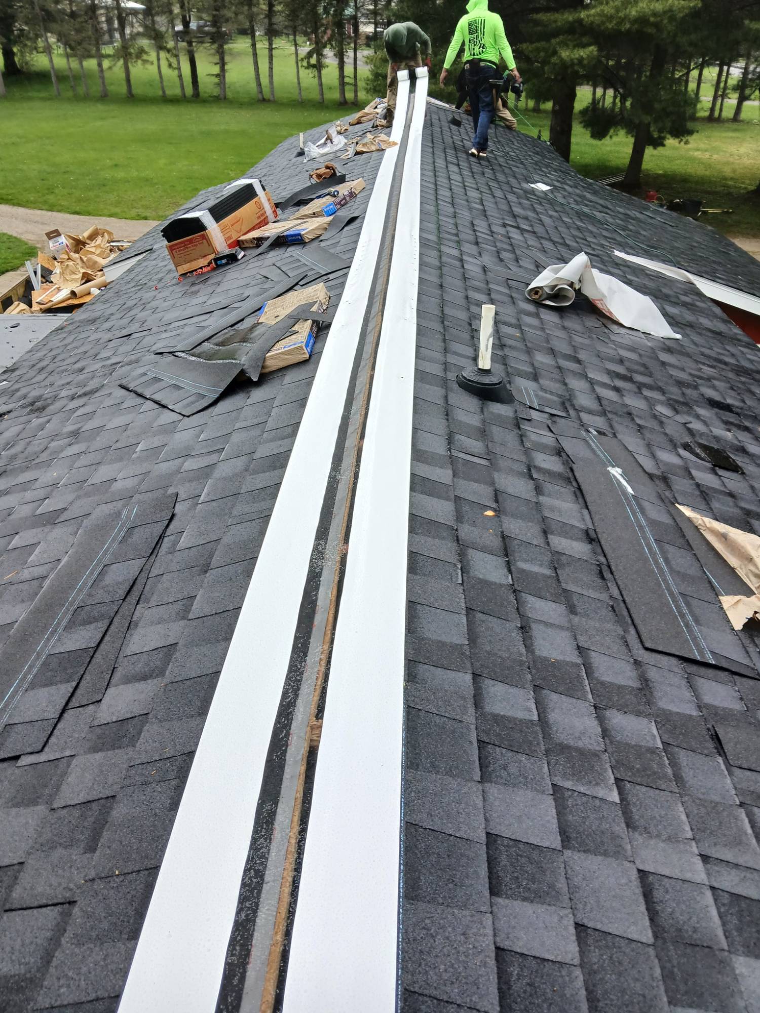 Billy White Roofing crew laying Attic Armor membrane along the ridge during a roof installation